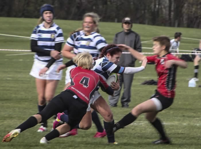 action shot of a rugby game, Kendra is making a tackle