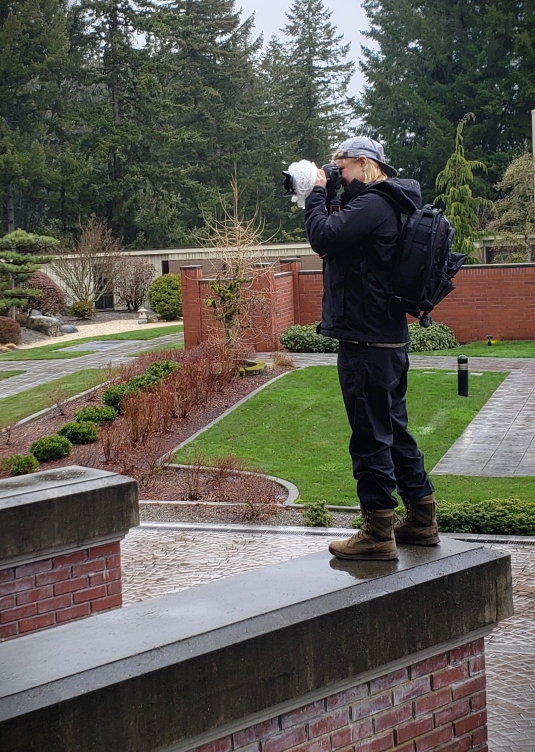 Kendra photographing in the rain up on a ledge